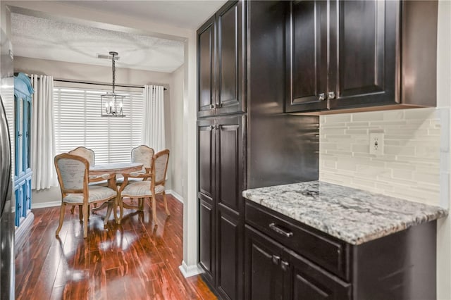 kitchen with pendant lighting, light stone counters, tasteful backsplash, and dark hardwood / wood-style floors