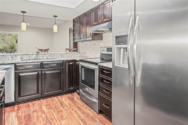 kitchen with sink, stainless steel appliances, decorative backsplash, decorative light fixtures, and light wood-type flooring