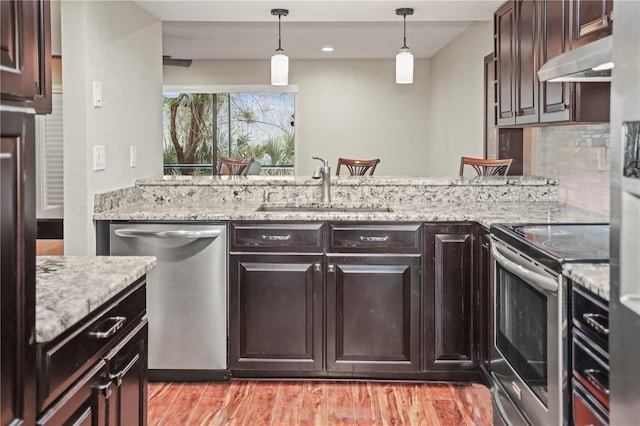 kitchen featuring sink, tasteful backsplash, light hardwood / wood-style flooring, pendant lighting, and stainless steel appliances