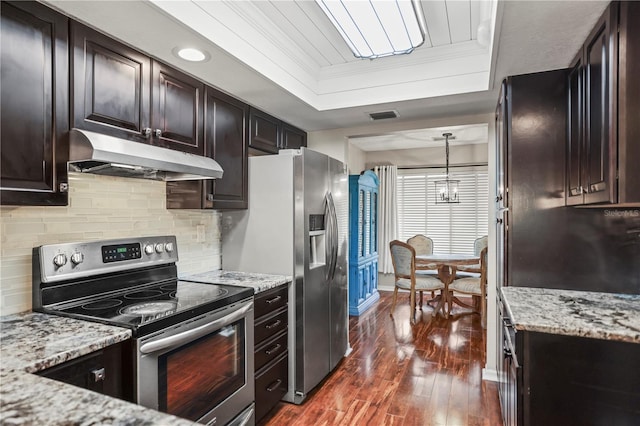 kitchen with pendant lighting, light stone counters, a tray ceiling, stainless steel appliances, and crown molding