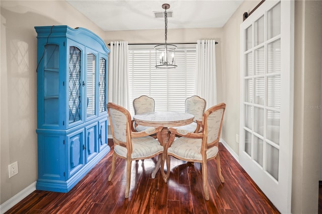 dining room featuring dark wood-type flooring, plenty of natural light, and an inviting chandelier