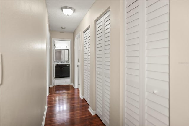 hallway with dark wood-type flooring and a textured ceiling