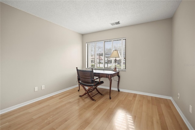 office with a textured ceiling and light wood-type flooring