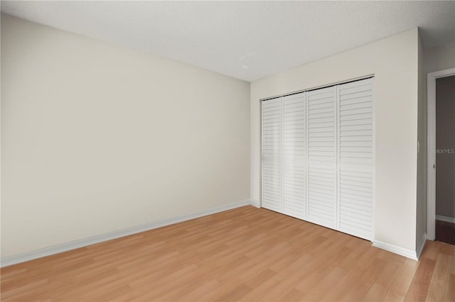 unfurnished bedroom featuring hardwood / wood-style flooring, a textured ceiling, and a closet