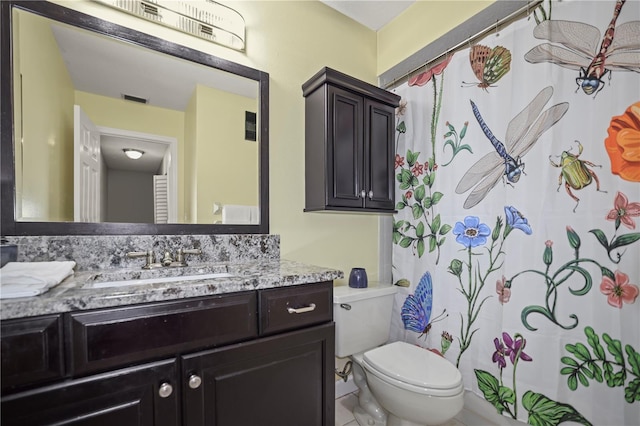 bathroom featuring vanity, walk in shower, and toilet