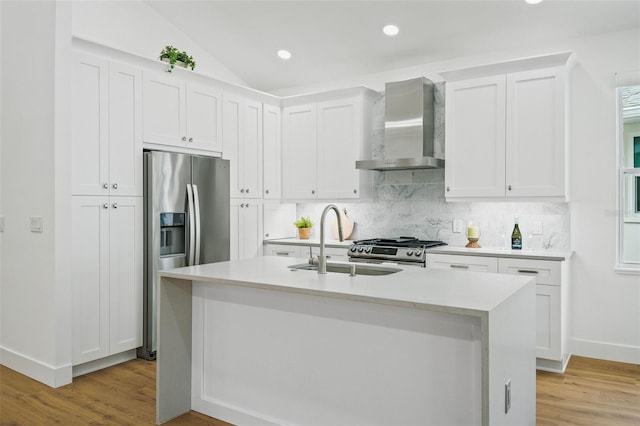 kitchen with a kitchen island with sink, wall chimney range hood, and white cabinets