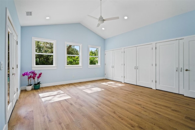 unfurnished bedroom with ceiling fan, vaulted ceiling, multiple closets, and light wood-type flooring