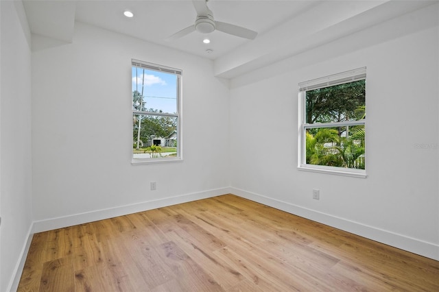 empty room featuring a wealth of natural light, ceiling fan, and light hardwood / wood-style flooring