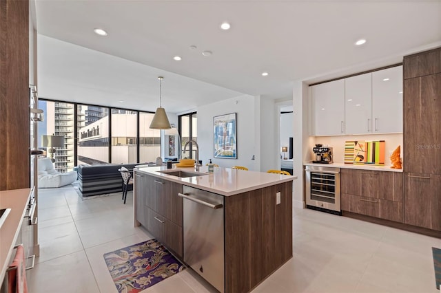 kitchen featuring pendant lighting, sink, wine cooler, white cabinets, and stainless steel dishwasher