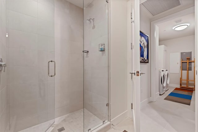 bathroom with a shower with shower door and washing machine and dryer