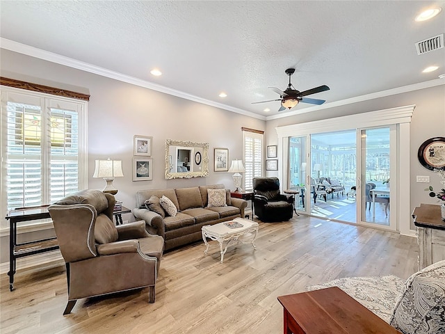 living room with ornamental molding, a textured ceiling, and light hardwood / wood-style flooring