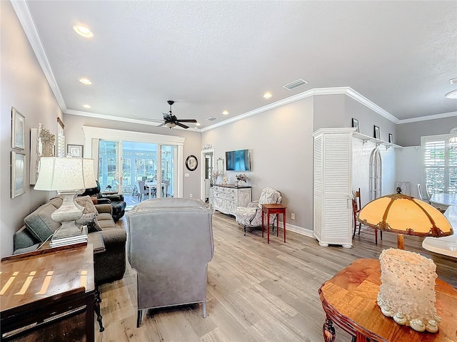 living room featuring crown molding, ceiling fan, a textured ceiling, and light wood-type flooring