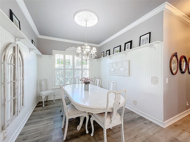 dining area with crown molding, hardwood / wood-style floors, and a notable chandelier