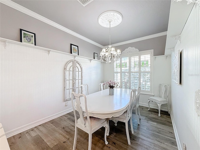 dining space with a notable chandelier, crown molding, and hardwood / wood-style flooring