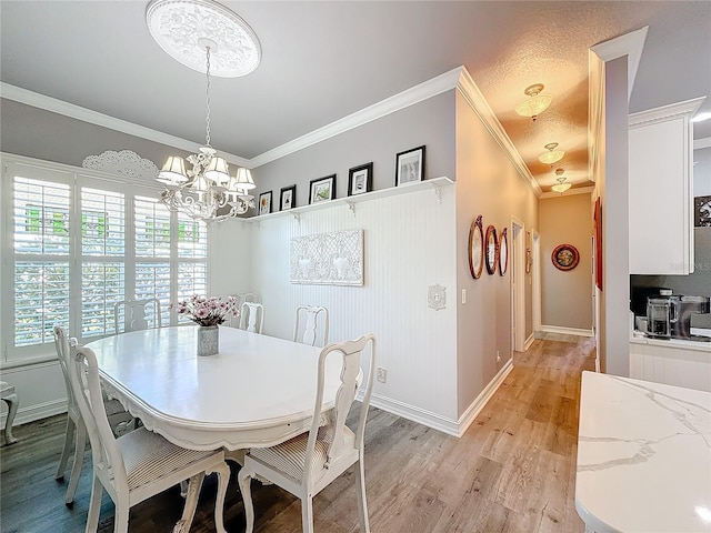 dining room featuring an inviting chandelier, ornamental molding, and light wood-type flooring