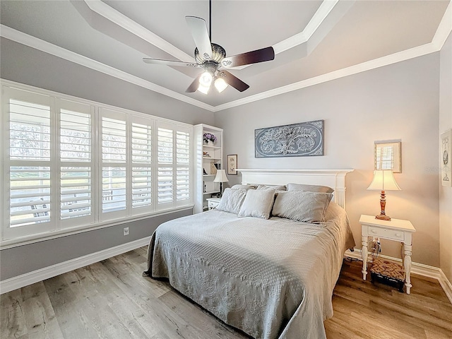 bedroom with hardwood / wood-style flooring, ornamental molding, a raised ceiling, and ceiling fan