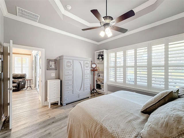 bedroom with ornamental molding, a raised ceiling, ceiling fan, and light wood-type flooring