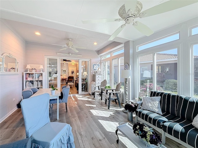 living room with wood walls, ceiling fan, and light wood-type flooring