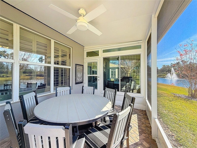 sunroom / solarium with plenty of natural light, ceiling fan, and a water view