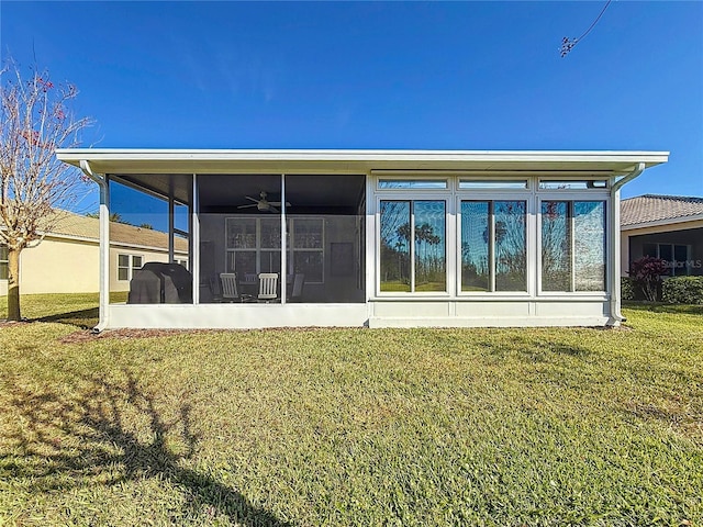 back of house with ceiling fan, a sunroom, and a lawn