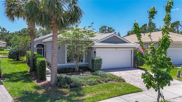 ranch-style home featuring a front yard, stucco siding, a tiled roof, an attached garage, and driveway