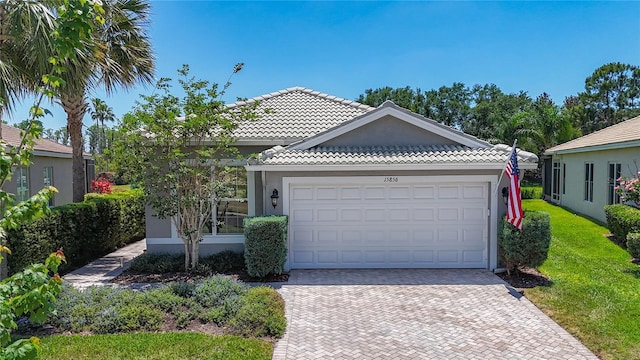 single story home with a tiled roof, decorative driveway, a garage, and stucco siding