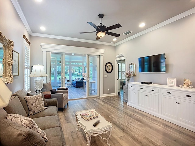 living area with visible vents, ornamental molding, baseboards, a ceiling fan, and light wood finished floors