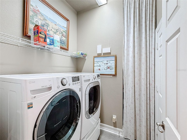 clothes washing area featuring separate washer and dryer, baseboards, and laundry area