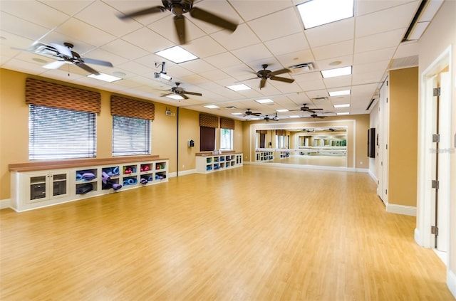 workout area with a ceiling fan, visible vents, baseboards, light wood finished floors, and a drop ceiling