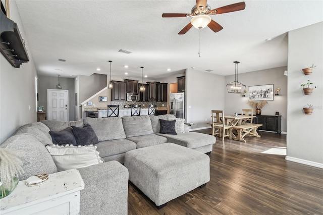 living room with dark hardwood / wood-style floors, ceiling fan with notable chandelier, and a textured ceiling