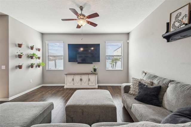 living room featuring ceiling fan, plenty of natural light, dark wood-type flooring, and a textured ceiling