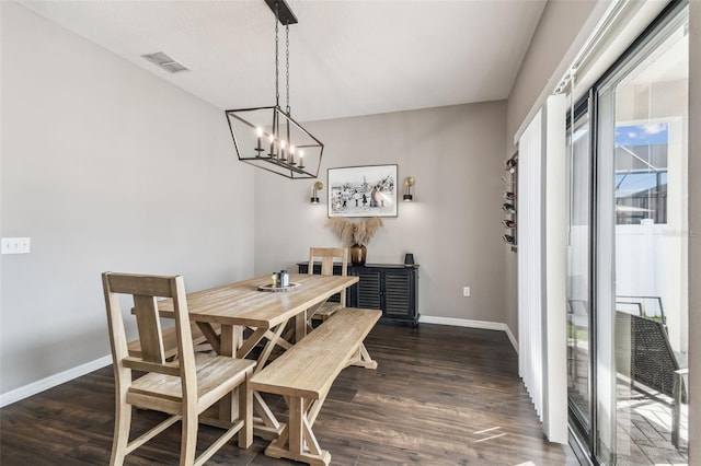 dining area with dark wood-type flooring and a chandelier