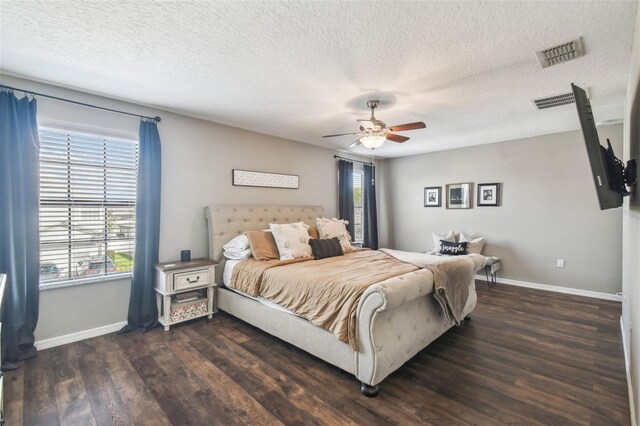 bedroom featuring ceiling fan, dark hardwood / wood-style flooring, multiple windows, and a textured ceiling