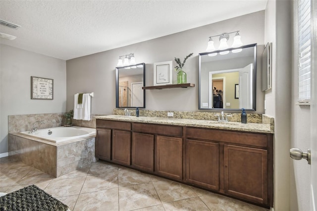 bathroom with vanity, tile patterned flooring, tiled bath, and a textured ceiling