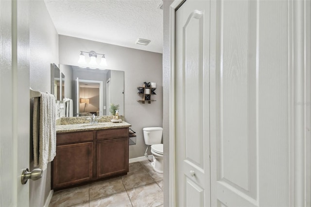 bathroom featuring vanity, tile patterned floors, toilet, and a textured ceiling