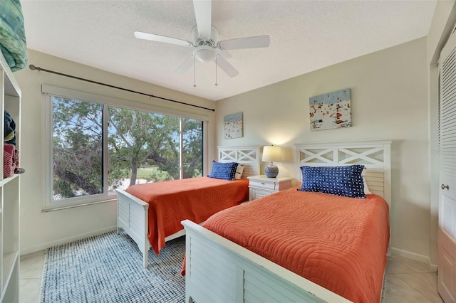 bedroom with ceiling fan, a textured ceiling, and light tile patterned floors