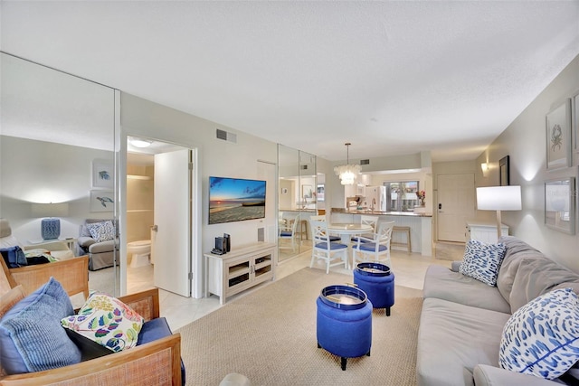 living room featuring an inviting chandelier, light tile patterned floors, and a textured ceiling