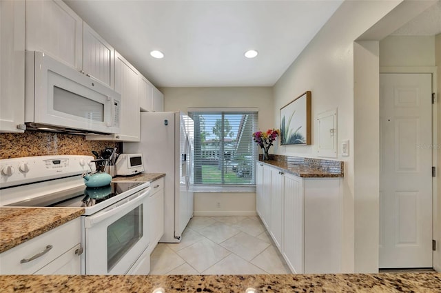 kitchen with stone countertops, light tile patterned floors, white cabinets, white appliances, and backsplash