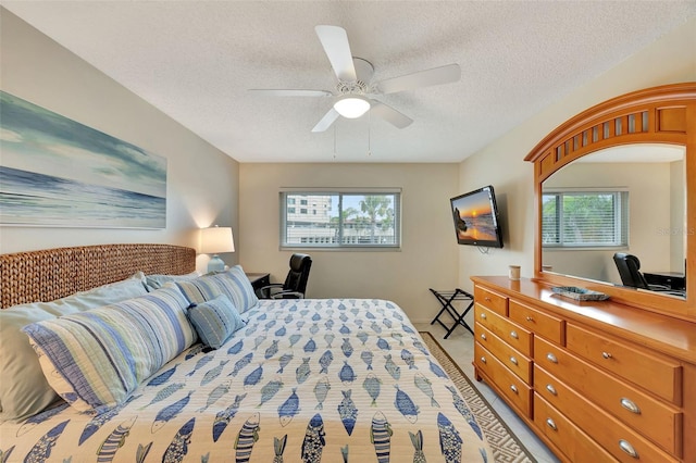 bedroom featuring ceiling fan, light carpet, and a textured ceiling