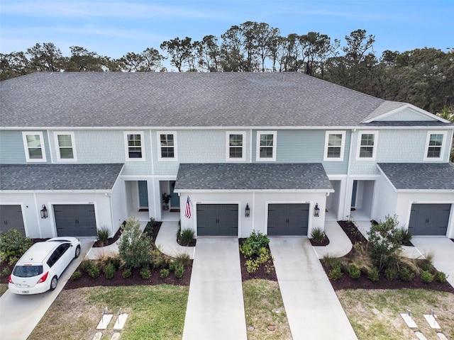 townhome / multi-family property featuring driveway, a shingled roof, a garage, and stucco siding