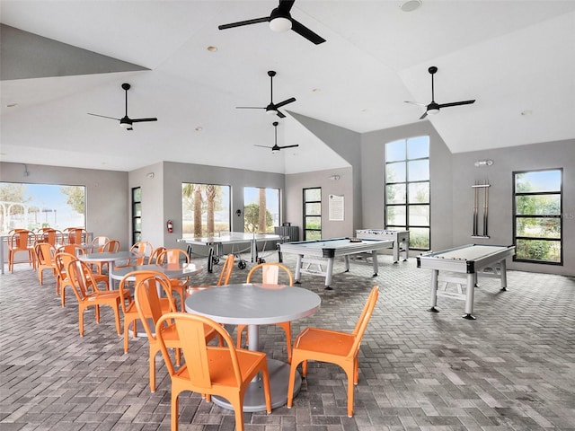 rec room featuring brick floor, plenty of natural light, and high vaulted ceiling