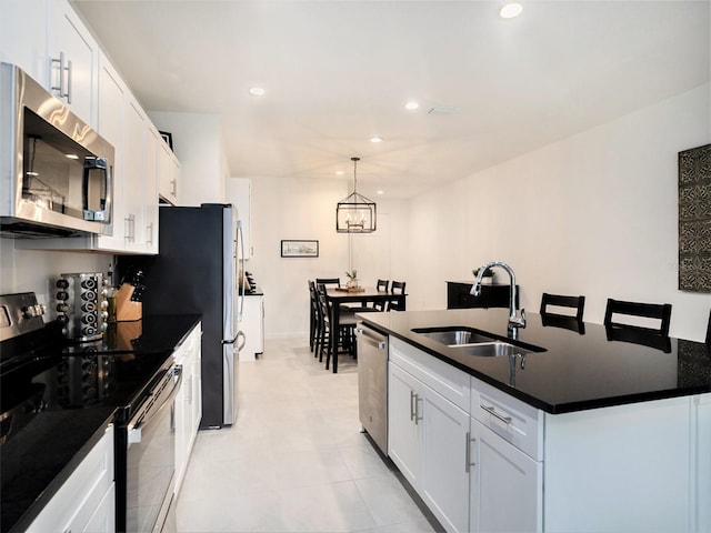 kitchen with white cabinets, dark countertops, appliances with stainless steel finishes, a sink, and recessed lighting