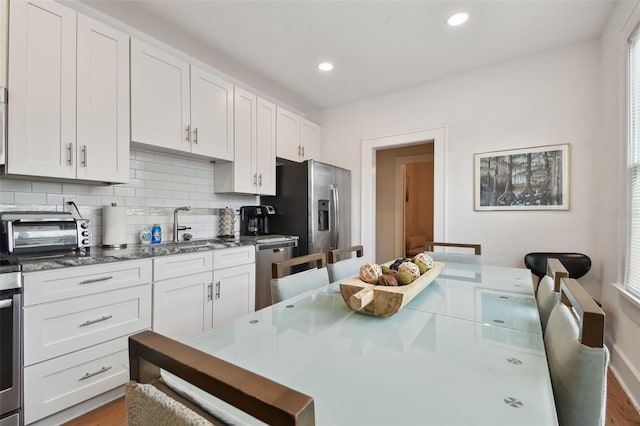 kitchen with sink, backsplash, stainless steel appliances, and white cabinets