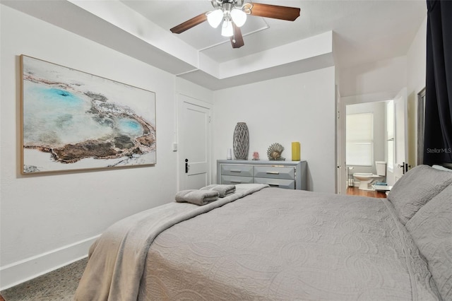 bedroom featuring ceiling fan, a raised ceiling, and ensuite bath