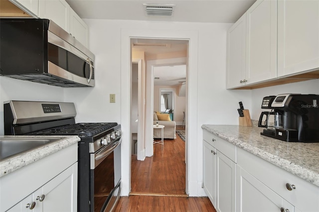 kitchen featuring white cabinetry, stainless steel appliances, dark hardwood / wood-style flooring, and light stone countertops