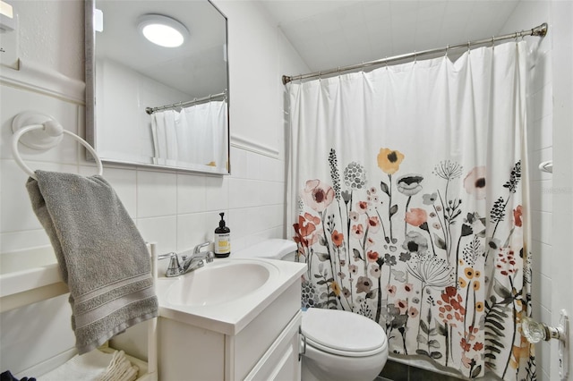 bathroom featuring vanity, toilet, curtained shower, and tile walls