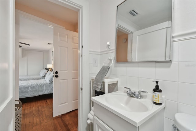 bathroom with vanity, toilet, wood-type flooring, and tile walls