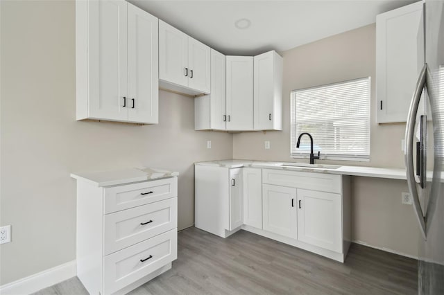 kitchen with sink, white cabinets, light wood-type flooring, and stainless steel fridge with ice dispenser