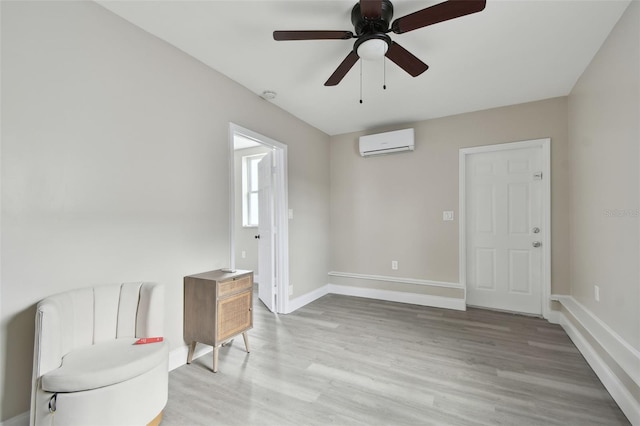 sitting room featuring ceiling fan, a wall mounted AC, and light wood-type flooring