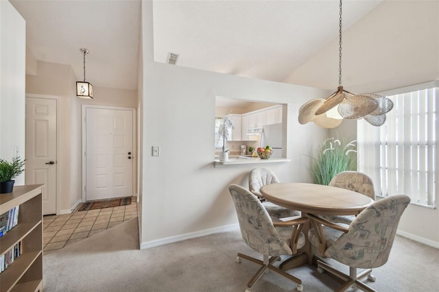 dining room featuring a healthy amount of sunlight, lofted ceiling, and light carpet